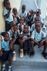 A group of orphaned children sitting on the stairs in their school uniforms