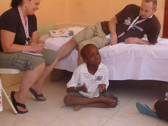 Kenzie sitting on the floor with the orphanage staff